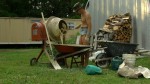 Man in short jean cut-offs, tending the cement mixer