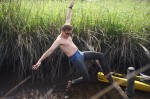 man in mid fall, wearing muddy jeans in the swamp