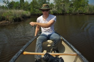 man in wet jeans and t-shirt, and shackles, paddling a canoe