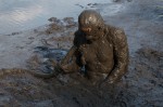 man, waist deep in swamp mud, covered in mud
