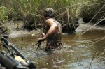 muddy man, pulling boat through swamp