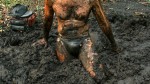 man in latex briefs, standing in deep swamp mud
