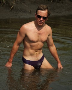 man in purple briefs, standing in water up to his thighs